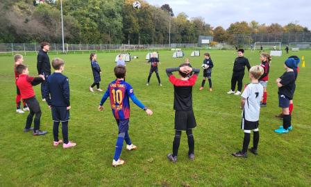 Kinder stehen im Kreis beim Fußballtraining auf dem Sportplatz.