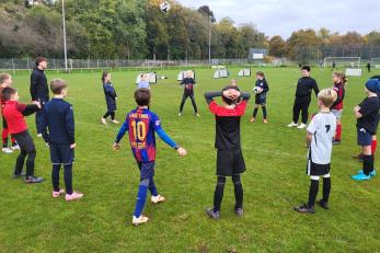 Kinder stehen im Kreis beim Fußballtraining auf dem Sportplatz.