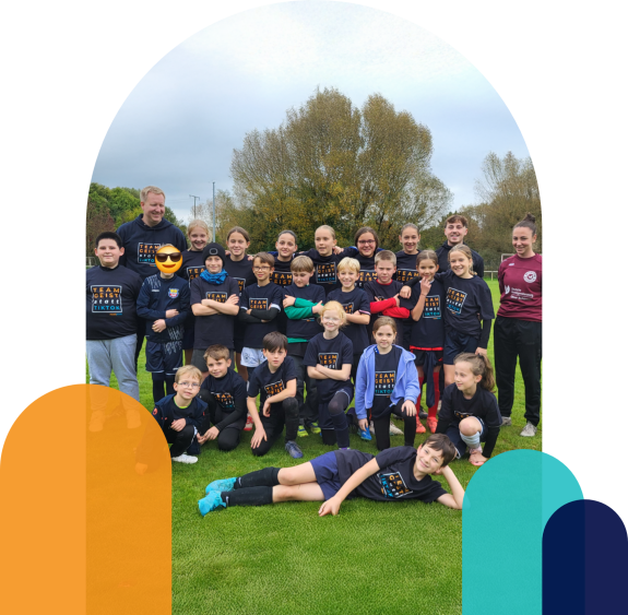 Kinder-Fußballgruppe mit Trainer posiert für Gruppenfoto auf dem Sportplatz