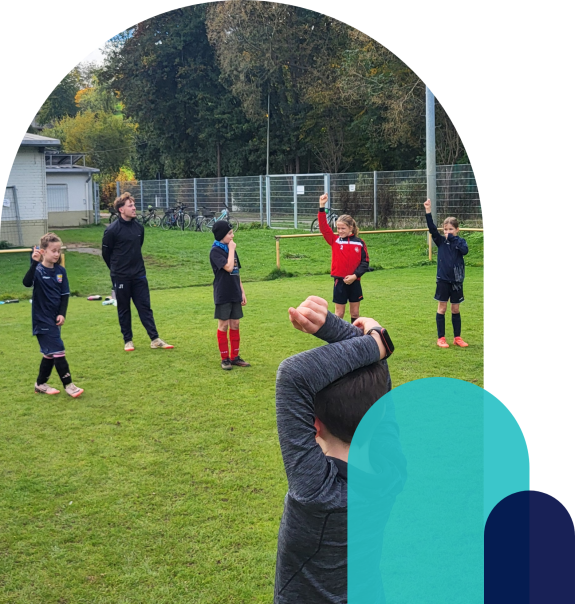 Kinder melden sich beim Fußballtraining auf dem Sportplatz.